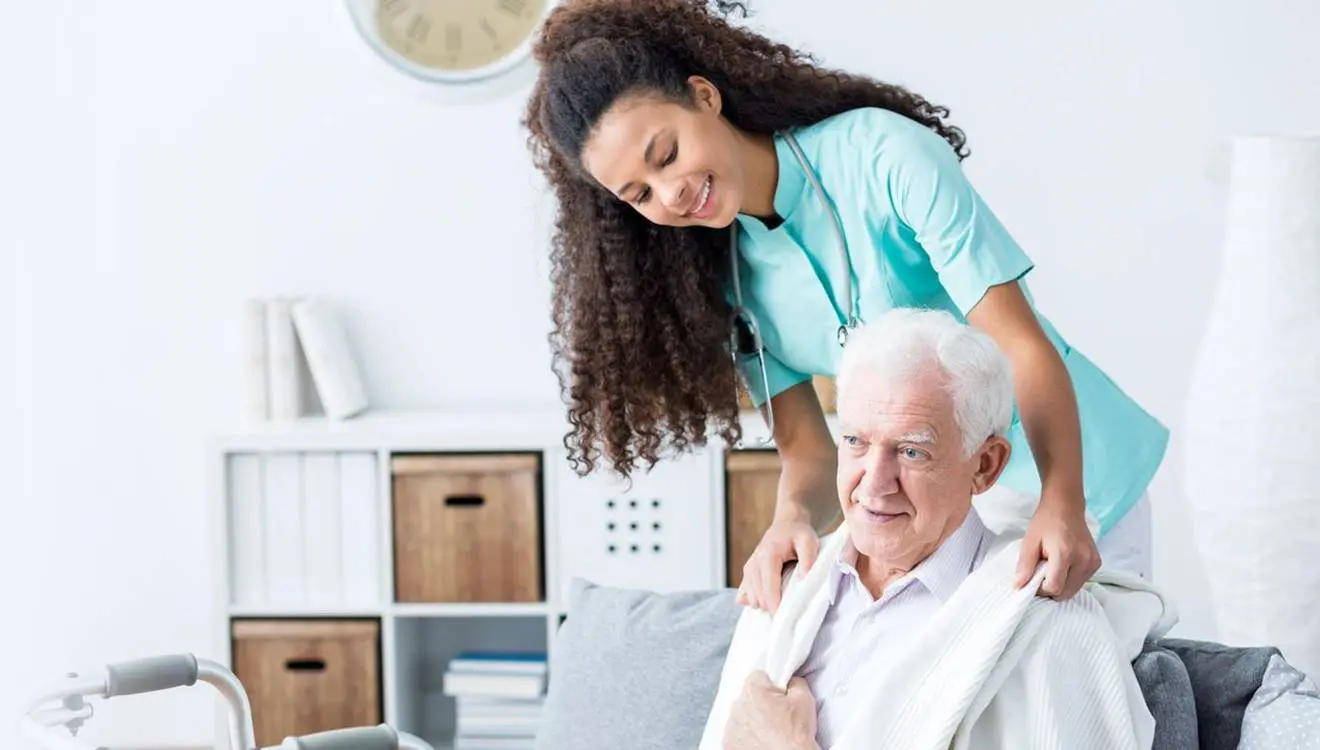 A woman helping an older man to get dressed