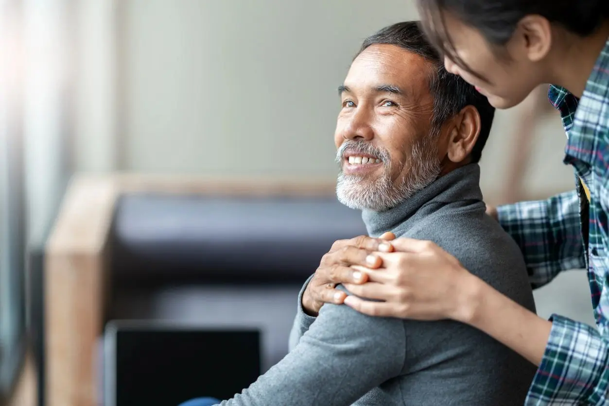 A woman is hugging an older man in his arms.